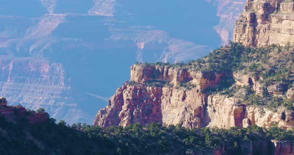 Overlooking the North Face of the Grand Canyon, a butte juts out over the chasm below. The air is ha alt