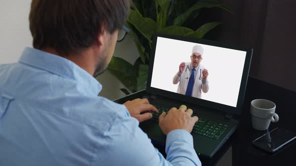Senior Male Doctor Wears White Medical Coat, Stethoscope, Headset Makes Distant Video Call. Old alt