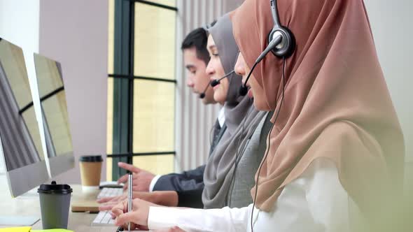 Asian mulsim customer service team talking on microphone headset working in call center office