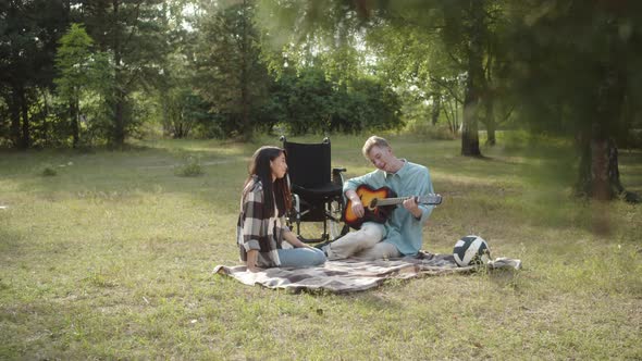 Being in the Public Park in a Good Weather Two Best Friends are Sitting on the Plaid a Disabled alt