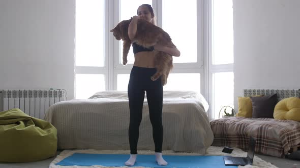 Young Athletic Woman in Sportswear with Cat on Hands Engaged in Fitness at Home
