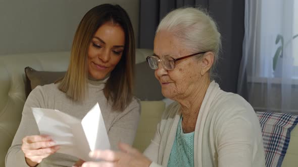 Senior Woman Reading a Letter with Female Volunteer