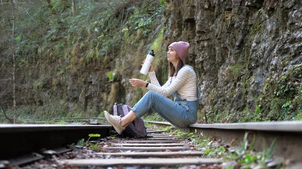 Young Backpacker Woman Is Sitting on Train Rail and Resting Alone