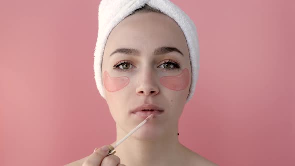Plesant nude girl applying collagen eye masks on face in front of a mirror alt