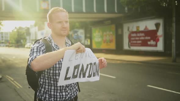 Time lapse of a man holding up his thumb for hitchhiking in London, back view, static shot alt
