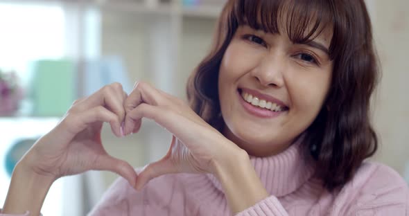 Smiling young woman showing heart with two hands