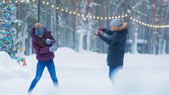 Couple Plays Snowballs Near Christmas Tree on Skating Rink