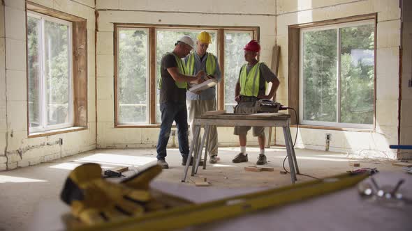 Three construction workers looking over blueprints at a commercial construction site