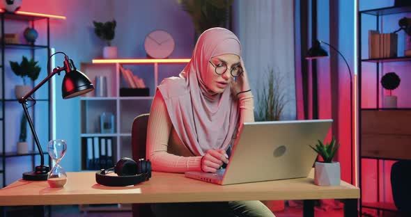 Muslim Woman in Hijab Sitting in front of Computer in Home Office and Working at Night alt