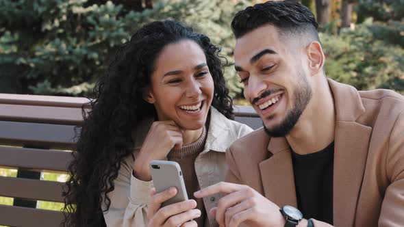 Bearded Guy with Attractive Girl in Autumn Park Sitting on Bench Cheerful Couple Interestedly Looks alt