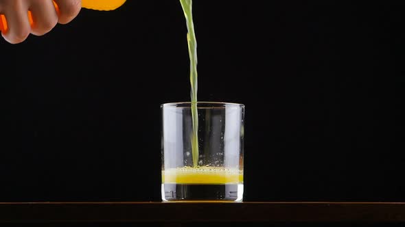 Man Pouring Orange Juice Soda in Glass in Slow Motion