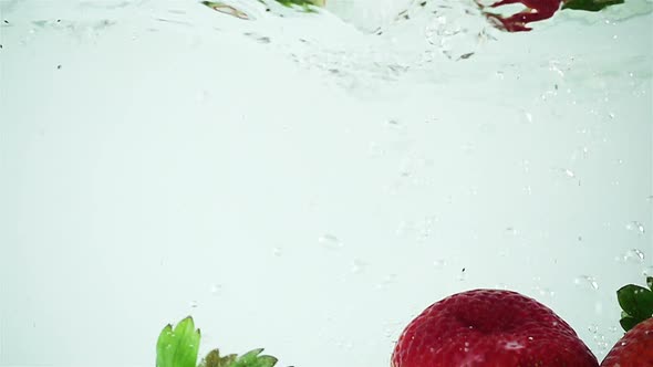 Ultra Slowmo Three Strawberries Splashed into Water on White Background alt