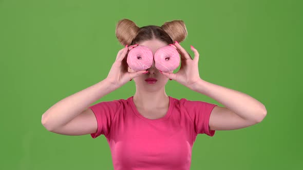 Girl Holds Donuts in Her Hands and Closes Her Eyes. Green Screen. Slow Motion alt