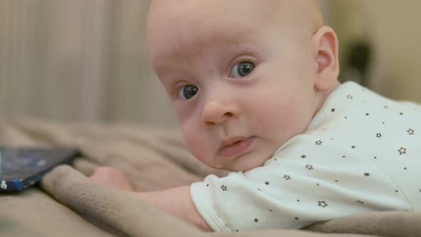 portrait of a smiling baby lying on his stomach on the bed