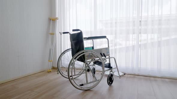 Empty modern wheelchair and walking stick or canes in hospital room. alt