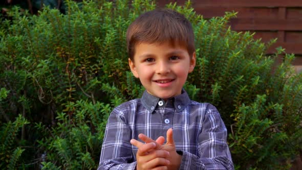The Adorable Little Boy Is Smiling and Counting on Fingers Outdoors alt