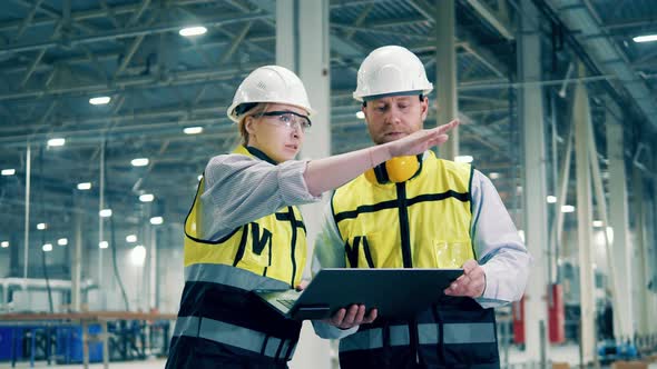 A Man and a Woman in Safety Wear are Discussing Factory Facility alt