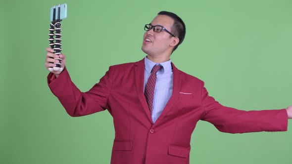 Happy Asian Businessman Vlogging with Phone alt