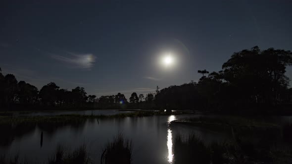 Time lapse 4K - Night with stars and moon rising at a lagoon. 