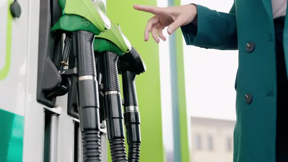 A woman fills up her car. green pistols at a gas station.  Petrol and Diesel.