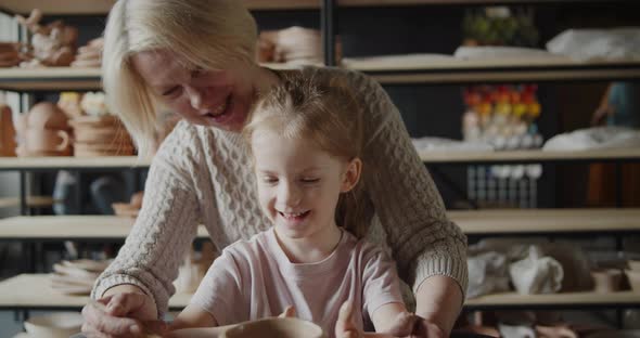 Grandmother Teaches Her Granddaughter Working on a Pottery Rotating Wheel