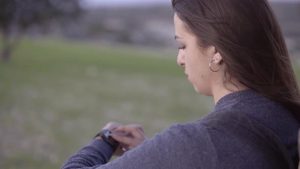 Young Woman Using Smartwatch to Check Text Messages Outdoors