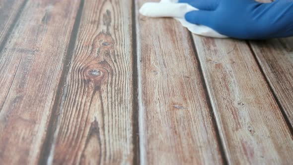 Man Hand in Blue Gloves Cleaning Wooden Surface  alt