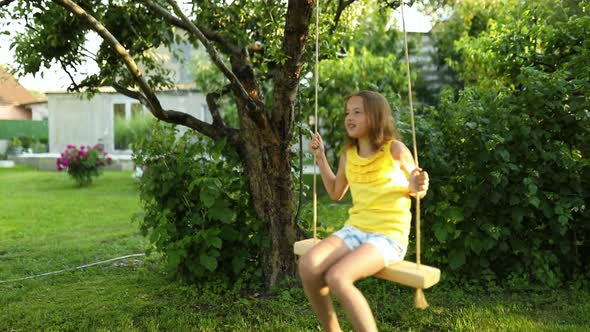 Happy barefoot laughing child girl swinging on a swing