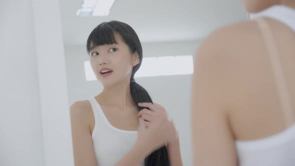 Beautiful face of young asian woman with happy smiling and touch cheek looking mirror. alt