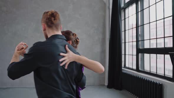 Man and Woman are Actively and Sensually Dancing a Tango in Gray Room