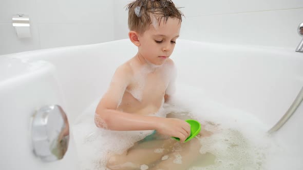 Happy Smiling Boy Washing in Bath and Playing with Colorful Toy Boats and Ships alt