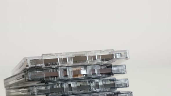 Stacked   compact  audio cassettes on white 4K 2160p 30fps UltraHD tilting footage - Retro music and alt
