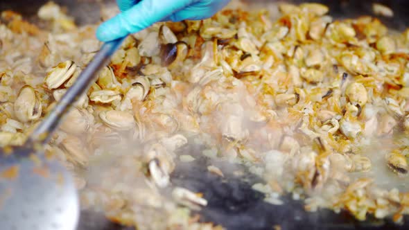 Cook fries mussels in a sauce in a large frying pan. Mussels.  Seafood delicacies. Clams. alt