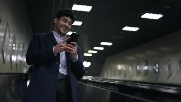 Low Angle View of the Successful Businessman Wearing Formal Clothes Reading News at His Smartphone alt