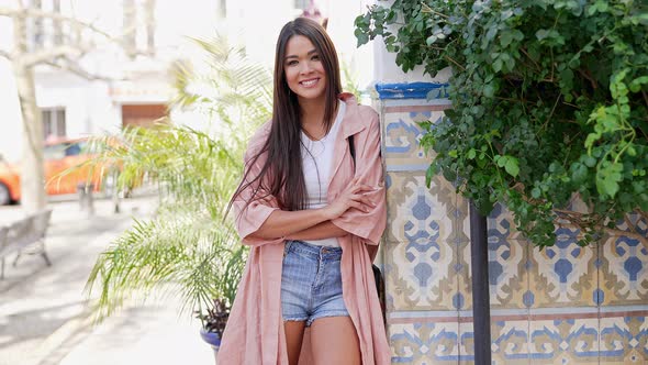 Joyful Stylish Ethnic Woman Standing Against Colorful Wall alt