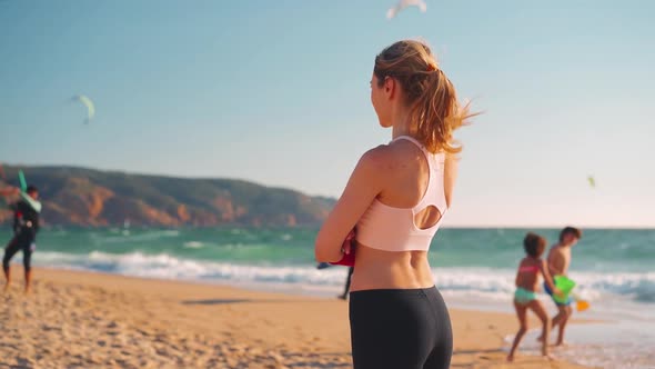 Slow Motion Young Adult Fit Woman Standing Ocean Beach Turns Around and Calls you Gesture alt