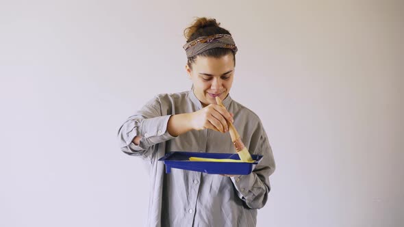 Brunette Mixes Paints in Blue Tray and Raises Brush Smiling