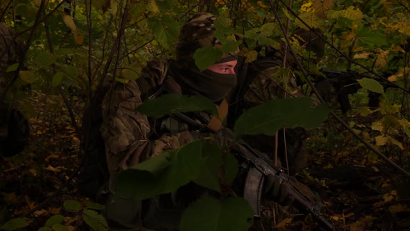Masked Commandos in the Forest. A Soldier with a Rifle Is Watching Closely. Special Forces Are alt
