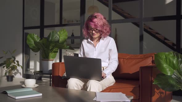 Young Woman Using Laptop at Home Office Working Online Sitting on Sofa alt