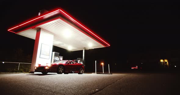 Woman In Jumpsuit Getting Out Of Red Ferrari At Gas Station alt
