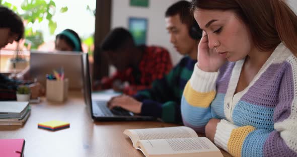 Multiracial students reading books and using laptop while studying together - School concept alt