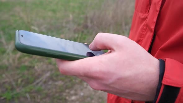 A Man Uses a Smartphone Surf the Internet on the Street