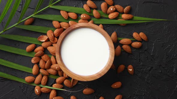 Amond Seeds with Bowl of Fresh Natural Milk Placed on Black Stone Background alt