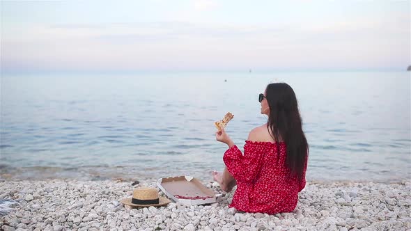 Woman Having a Picnic with Pizza on the Beach