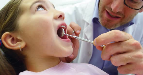 Dentist examining a young patient with dental tools alt