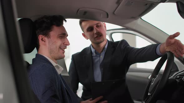 Business Car Male Professional Manager Shows a New Vehicle Model to a Joyful Buyer in a Automobile