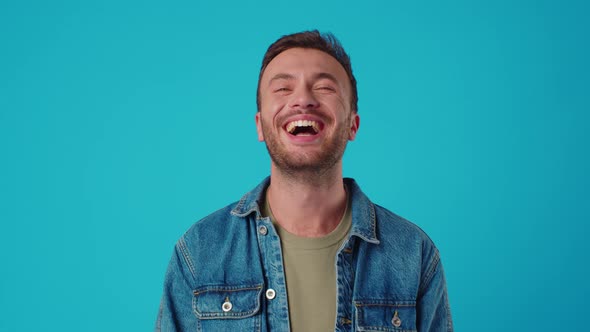 Young Caucasian Man Smiling Against Blue Studio Background