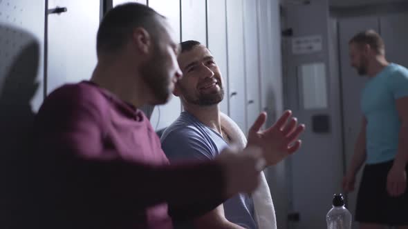 Positive Caucasian Sportsmen Sitting in Locker Room After Training and Talking. Smiling Handsome alt