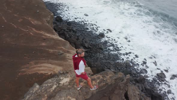 A Tourist Stands on the Edge of the Shore Surrounded with Ocean Waters alt