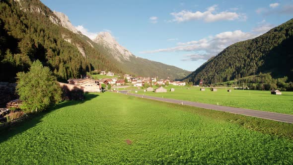 Aerial View of an Austrian Village in a Green Mountain Valley at Sunset Alps alt